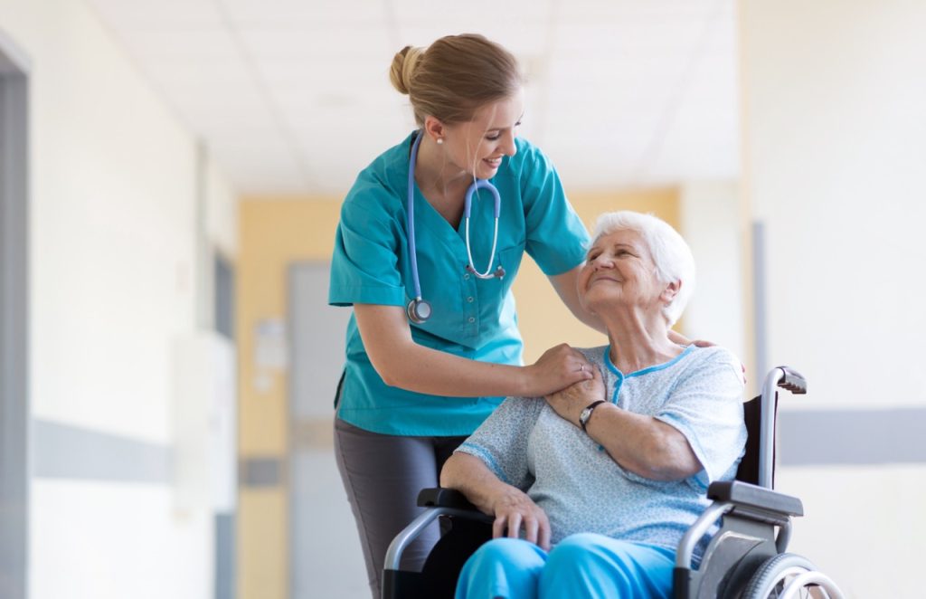 CNA comforting senior woman in wheelchair