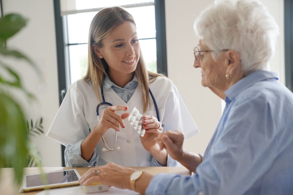 nursing assistant with trained medication administration providing senior with prescription