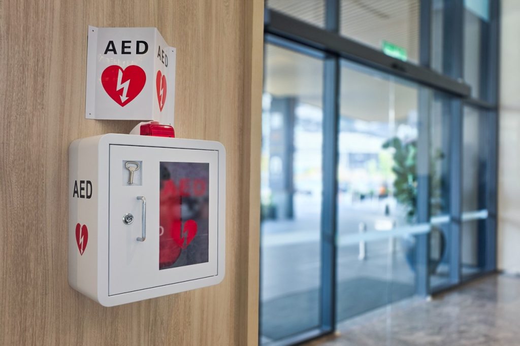 AED in a lock box with a sign for clear visibility on a business wall as first aid in medical emergency situation